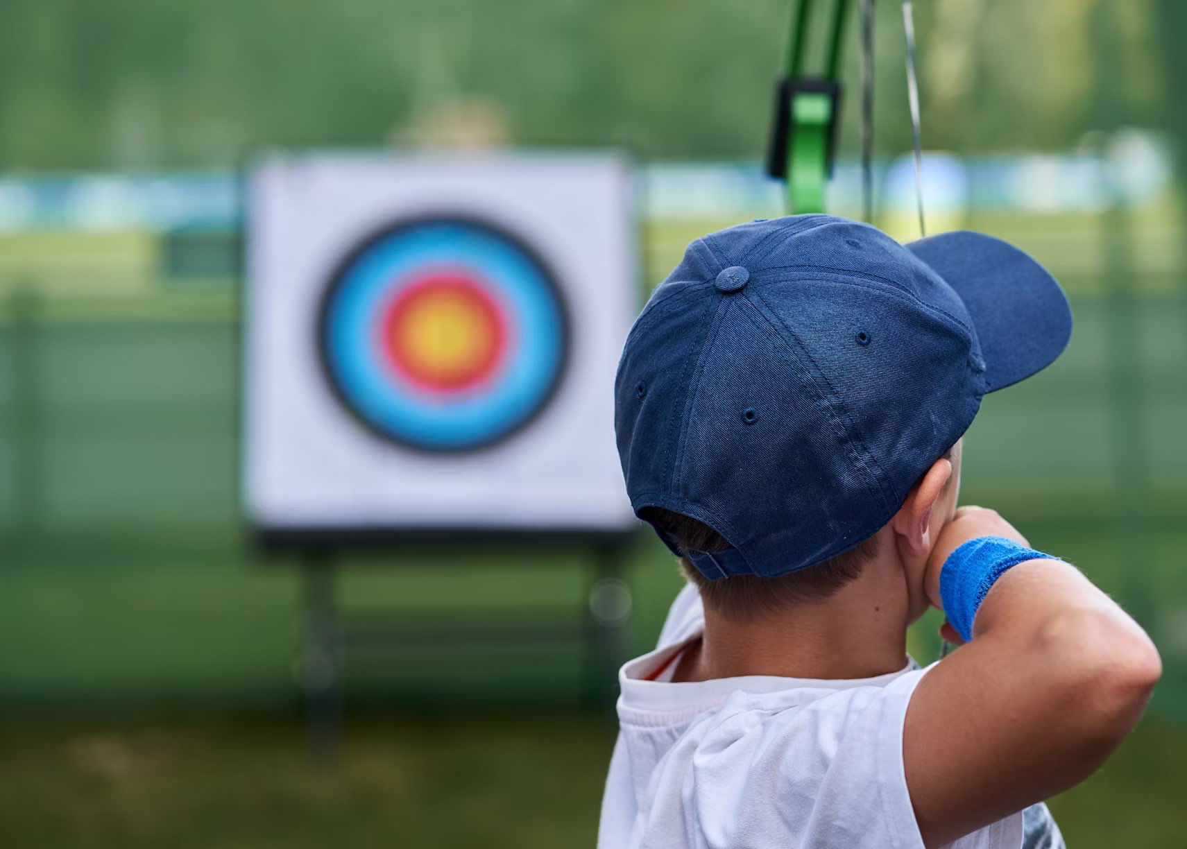 Photo of young boy at archery field, lining arrow up with target